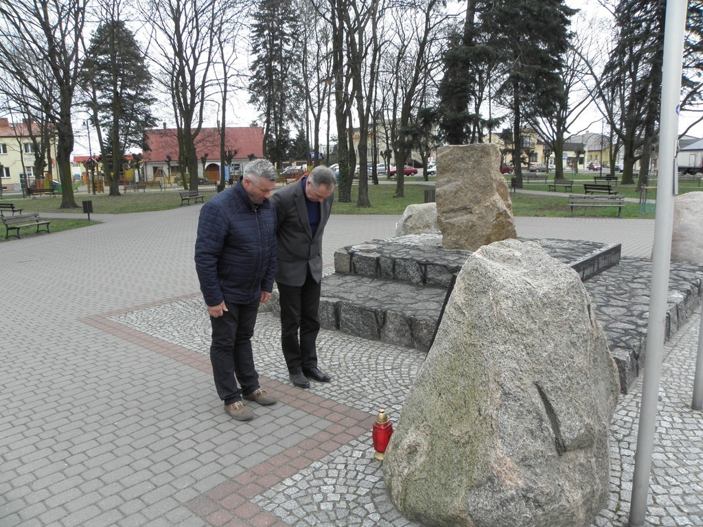 Wójt i Przewodniczący Rady Gminy Babiak stoją przed pomnikiem ofiar zbrodni katyńskiej.